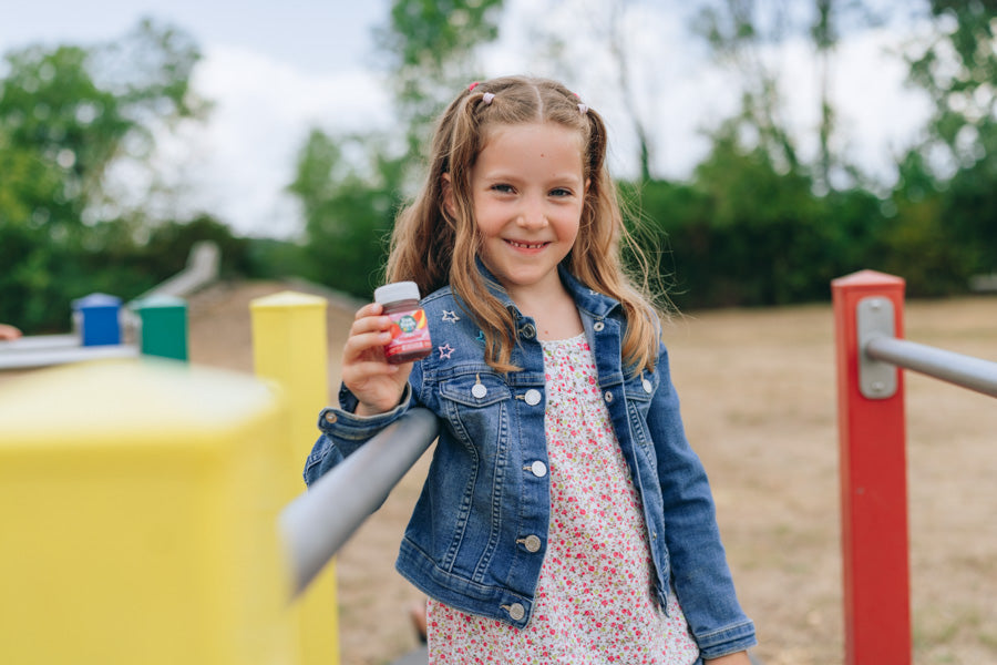 Mädchen auf einem Spielplatz präsentiert einen LiveFresh Kids Shot Erdbeere in der Hand.