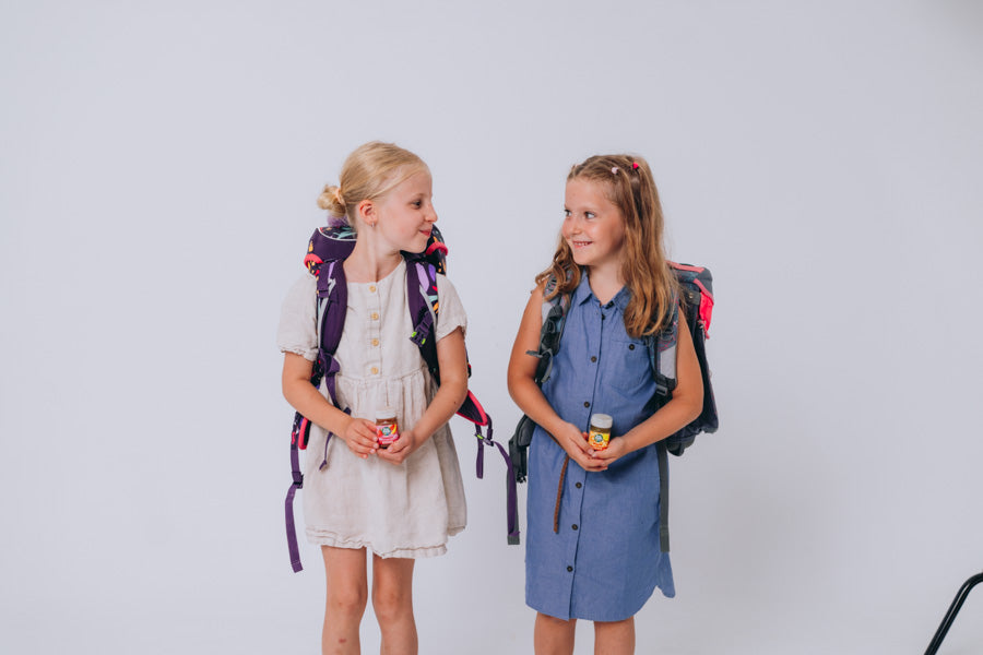Zwei Mädchen mit Schulranzen halten LiveFresh Kids Shots in den Händen.